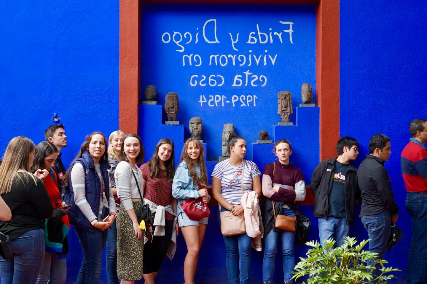 一排赌博娱乐平台网址大全的学生站在一面写着西班牙文的蓝色墙壁前